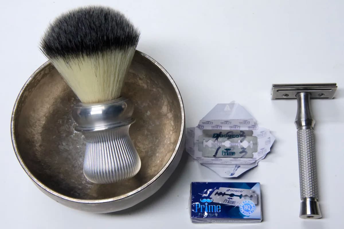 Dorco Prime Platinum 5-blade pack and a wax-paper-wrapped blade next to the ORMIXA Vector 316L safety razor, an ORMIXA titanium bowl and a Harbor synthetic brush