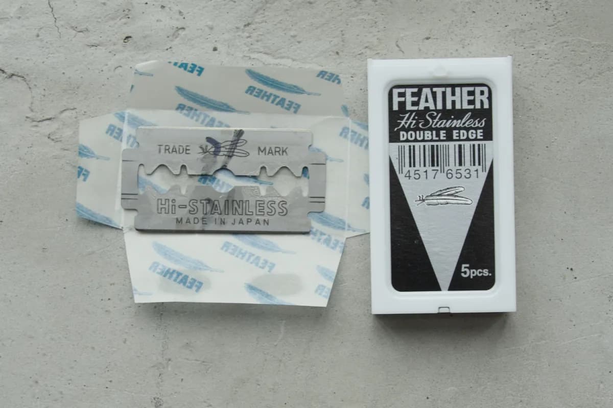 Feather Hi-Stainless blade stamped Made in Japan on its wrapper, beside the white five-blade case labelled Double Edge