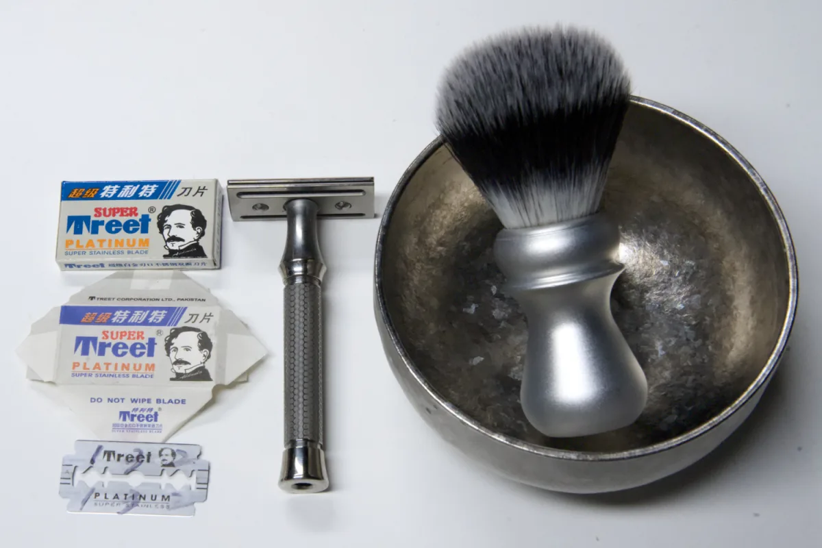 Super Treet Platinum DE blade pack, its printed paper wrapper and a loose blade beside the ORMIXA Vector TC4 safety razor, a Harbor synthetic brush and an ORMIXA titanium double-wall bowl on a white surface