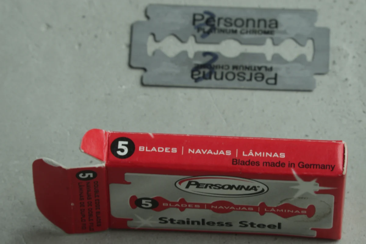 Red Personna five-blade box showing Stainless Steel and Blades made in Germany, with a loose Personna Platinum Chrome stamped blade above it