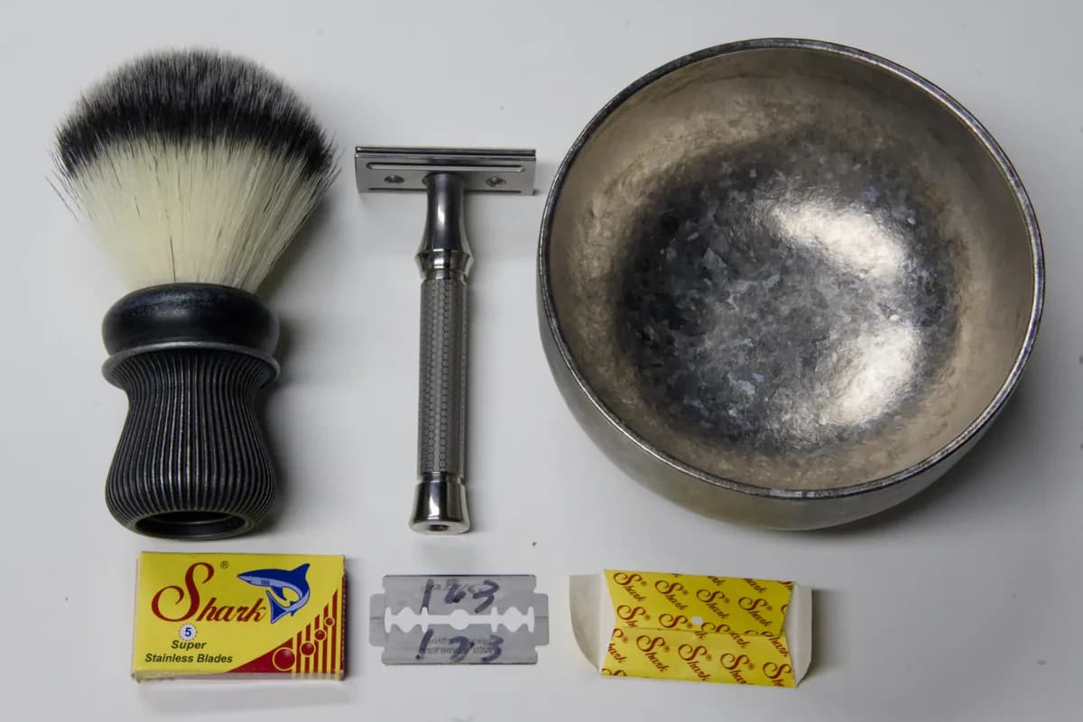 Shark Super Stainless DE blade pack, a loose blade and its wax wrapper beside the ORMIXA Vector TC4 safety razor, a Harbor synthetic brush and an ORMIXA titanium double-wall bowl on a neutral surface