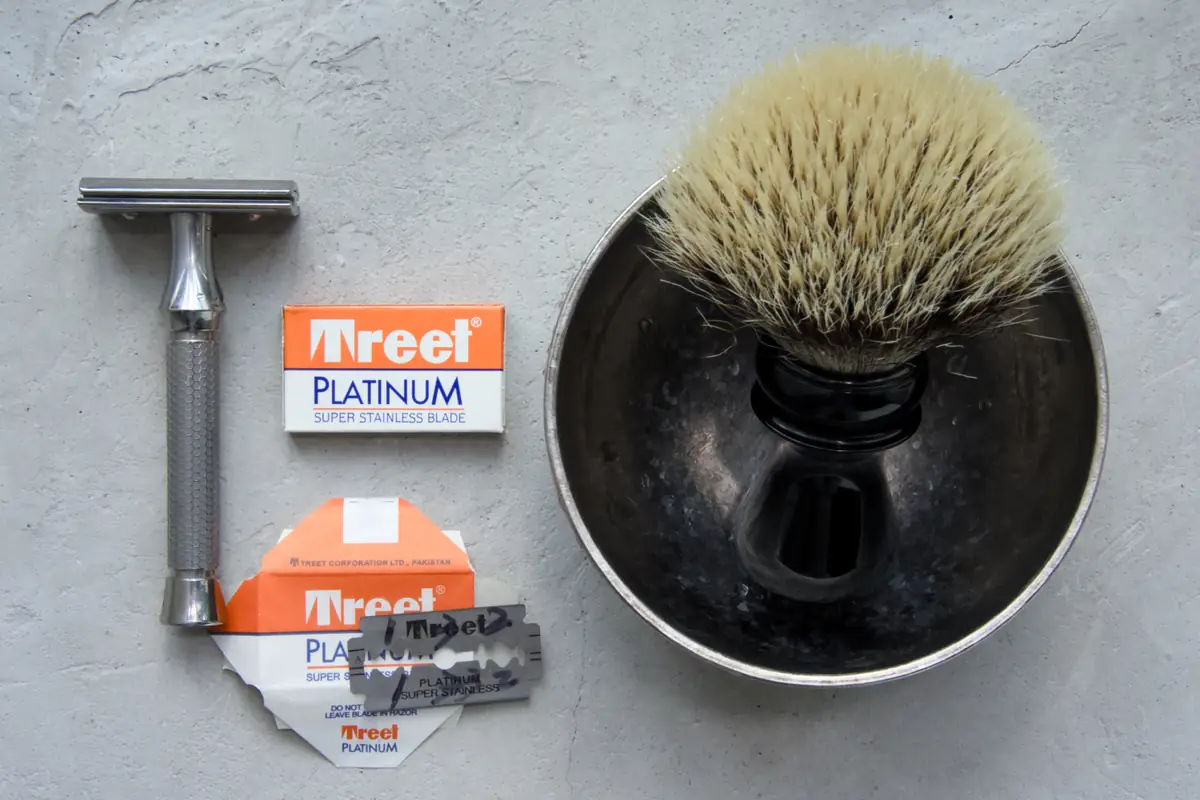 Treet Platinum Super Stainless DE blade pack, its printed paper wrapper and a loose blade beside the ORMIXA Vector TC4 safety razor, a Harbor badger brush and an ORMIXA titanium double-wall bowl on a neutral surface